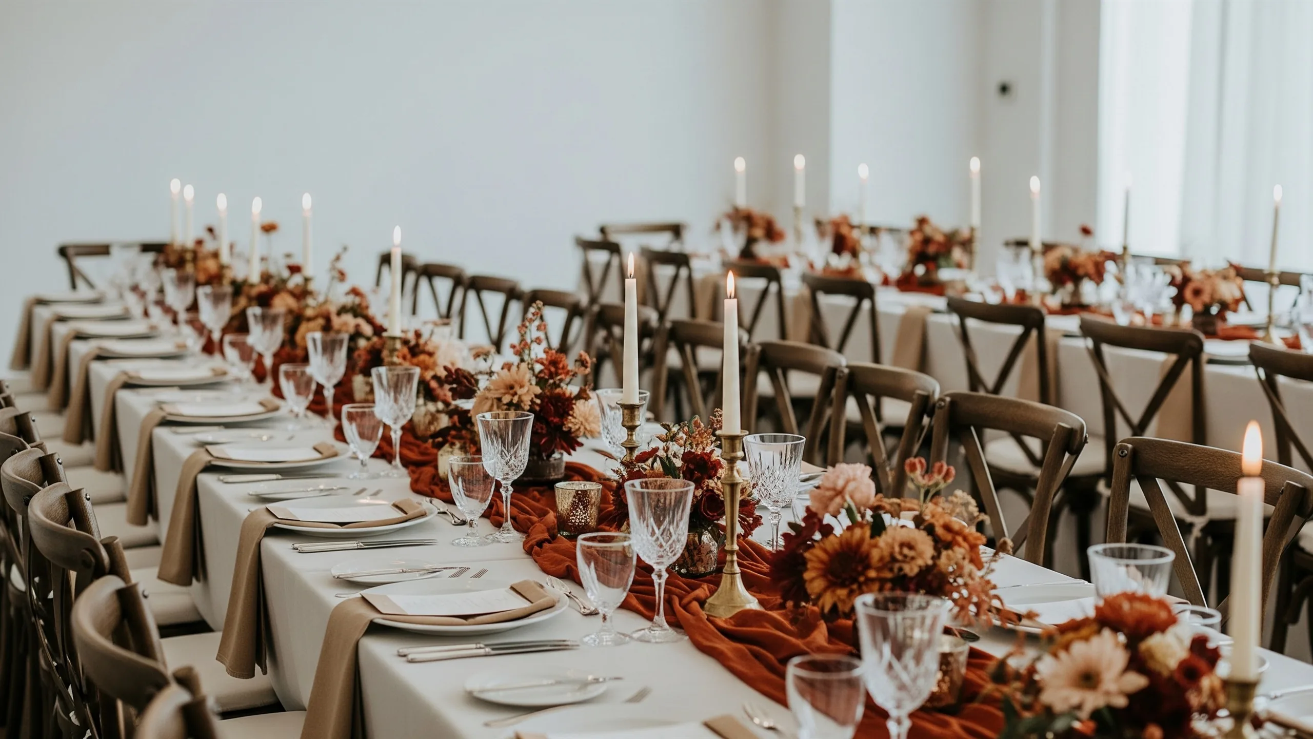 A premium long-table dinner for an intimate Indian wedding, rich linens, brass candleholders, floral runners, crystal glassware with no cards, in context