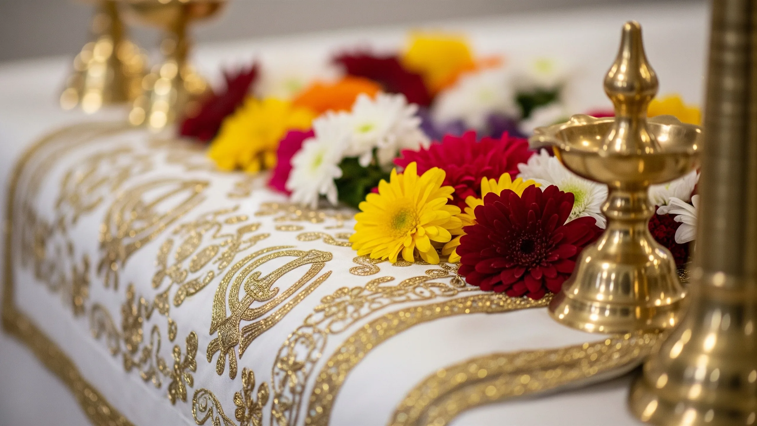A close detail of embroidered rumala sahib fabric, fresh flowers and polished brass elements in a respectful gurudwara setting, no text, close-up detail